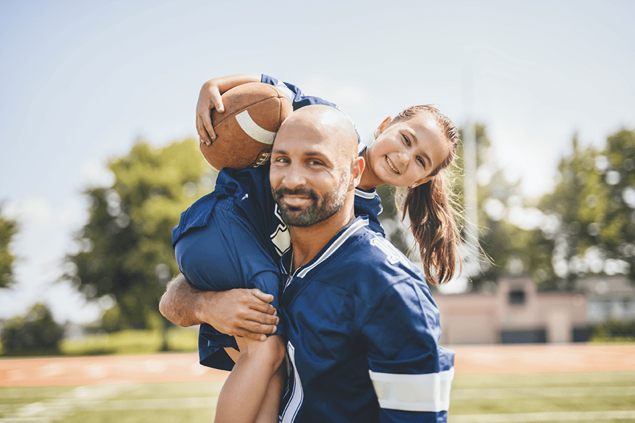father lifting daughter with football